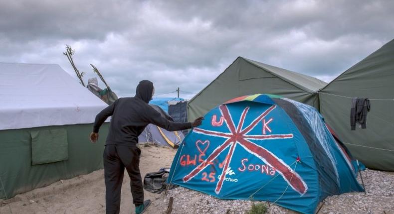 A Sudanese man stands next to a tent painted with the British flag at the Jungle migrant camp in Calais on October 12, 2016