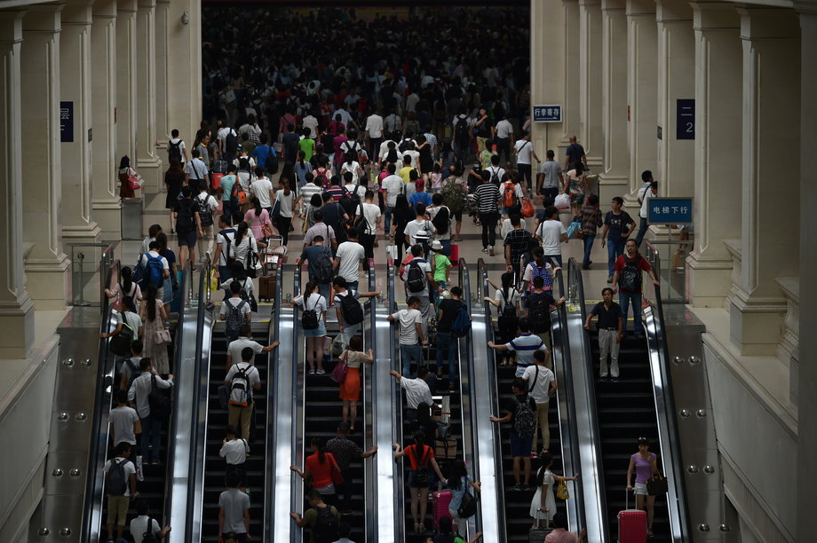 Ludzie udający się do ruchomych schodów, aby dostać się do torów kolejowych.