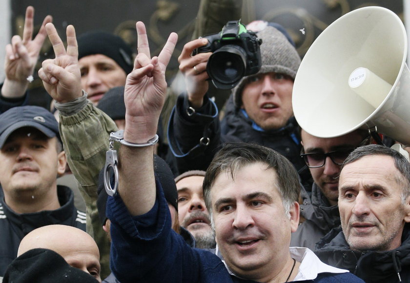 Supporters of Georgian former President Mikheil Saakashvili break a window a police car carrying Saa