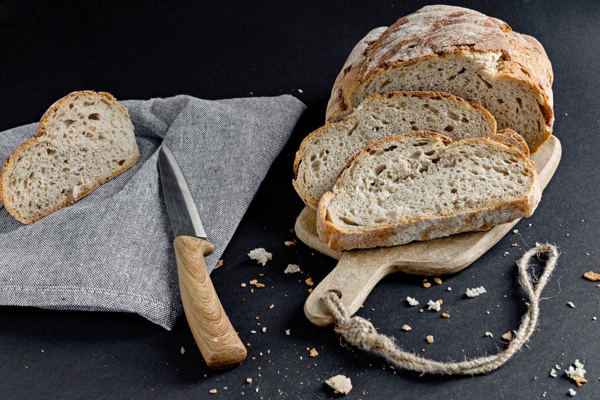Freshly,Baked,Artisan,Bread,Loaf,With,Knife,On,Wooden,Cutting