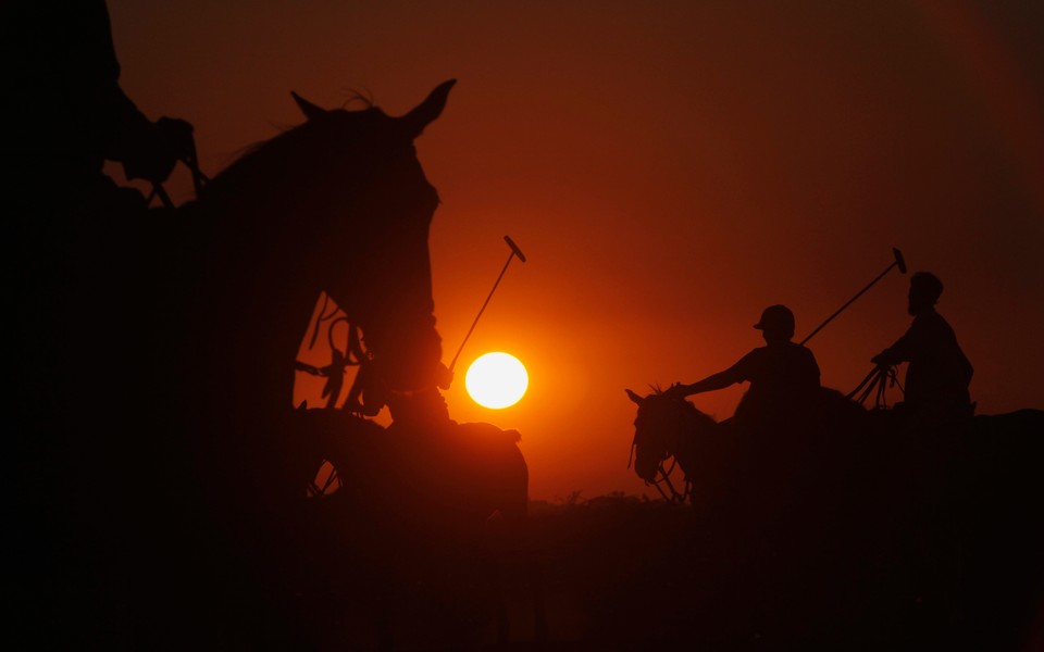 Players are silhouetted during a practice polo match along Karachi's Clifton beach