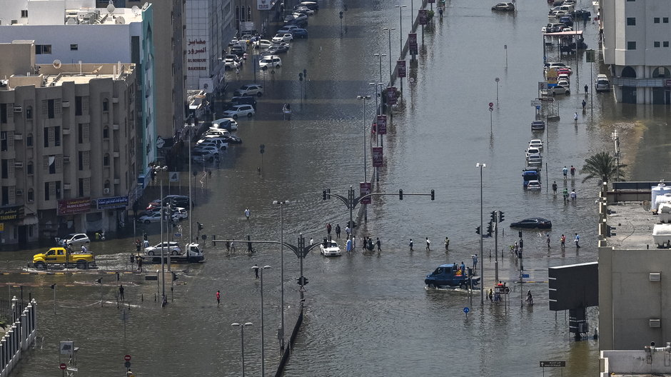 Ludzie przechodzą przez zalaną ulicę w Szardży 20 kwietnia 2024 r.