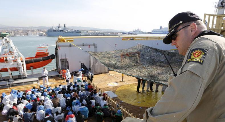 A crew member looks on as migrants wait to disembark from the Norwegian vessel Siem Pilot at Catania's harbour, Italy, June 30, 2015. REUTERS/Antonio Parrinello