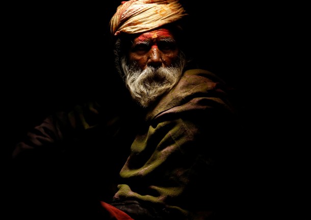 Light illuminates a Hindu holy man, or sadhu, as he sits at the premises of Pashupatinath Temple dur