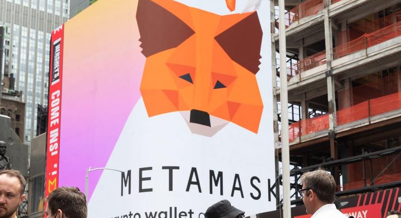 People stand by a Metamask billboard in Times Square during an NFT conference in New York City.