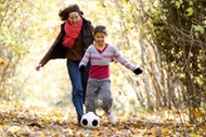 Mid adult woman and her daughter playing with a soccer ball