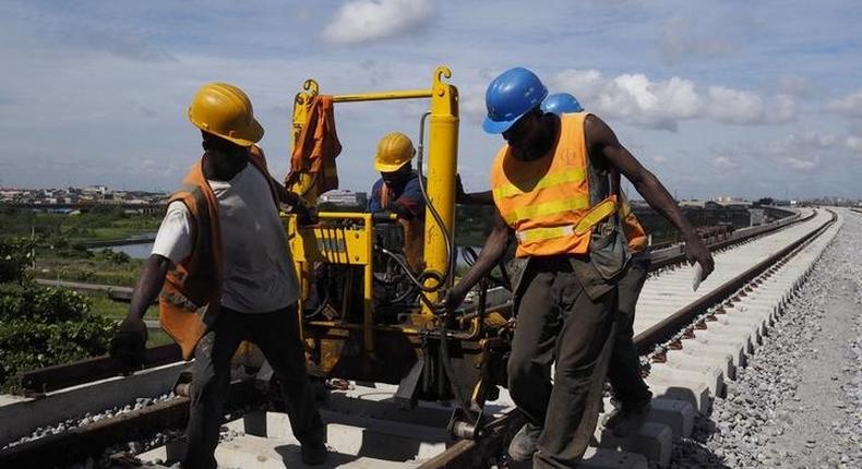 Men work on a train track at the National Arts Theatre stop of the light rail system under construction in Lagos, Nigeria, May 30, 2014.    REUTERS/Joe Penney