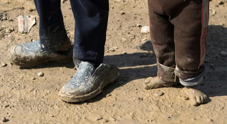 Displaced Iraqi children from Mosul walk in the mud towards refugee camps on March 24, 2017