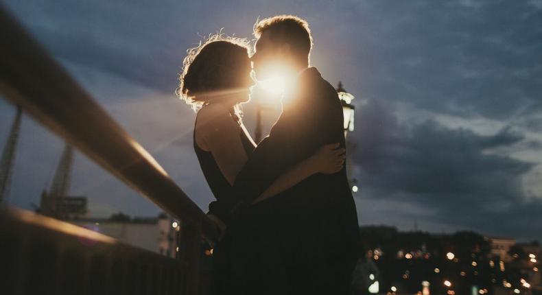 Caucasian couple kissing near railing at night