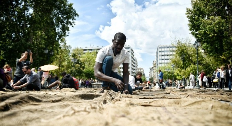 Ghanian artist Ibrahim Mahama performs Check Point - Prosfygika on the main Syntagma square in Athens on April 7, 2017 on the eve of the opening of the 14th edition of the Documenta 14 art exhibition