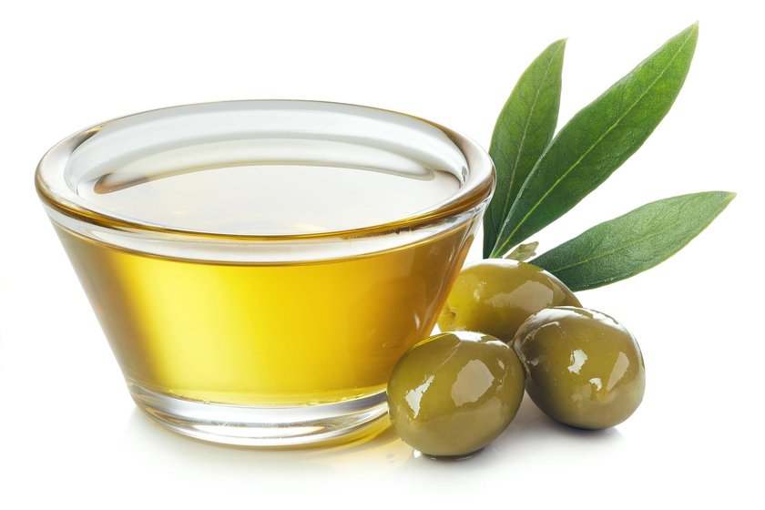 Bowl of olive oil and green olives with leaves