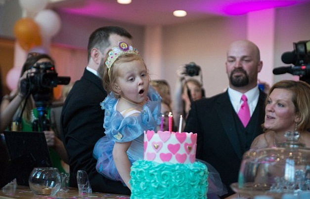 Pięciolatka zdmuchuje świeczki z tortu urodzinowego