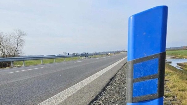 Modrý stĺpik pri diaľnici bez odstavného pruhu. MNa okraji vozovky pred mostnou konštrukciou. 
