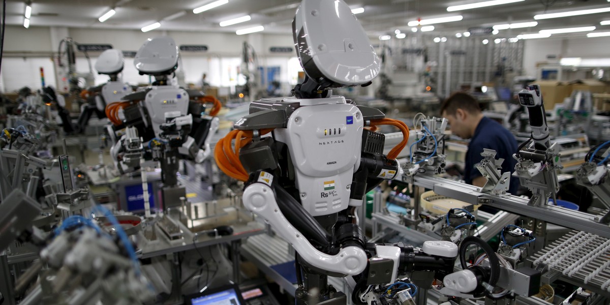 Humanoid robots work side by side with employees in the assembly line at a factory of Glory Ltd., a manufacturer of automatic change dispensers, in Kazo, north of Tokyo, Japan, July 1, 2015.