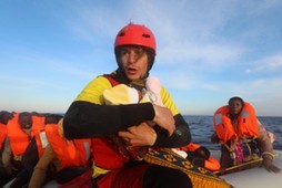 Spanish rescuer Daniel Calvelo carries a four-day-old baby girl into a RHIB, during a search and res