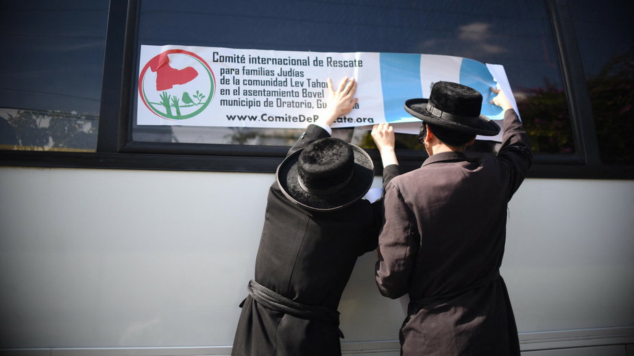 Członkowie ortodoksyjnej gminy żydowskiej umieszczający plakat "Międzynarodowego Komitetu Ratunkowego dla Rodzin Żydowskich z Osiedla Lev Tahor" na oknie autobusu (zdjęcie z września 2016 r.) 