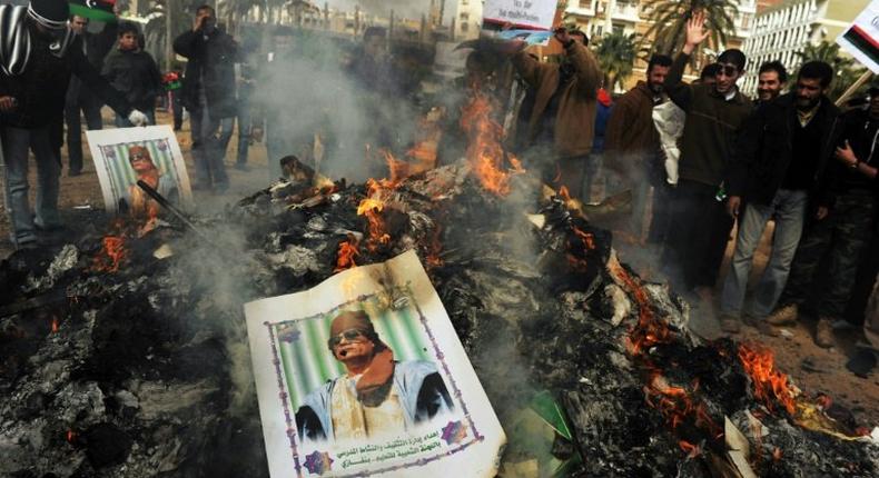 A portrait of Libyan strongman Moamer Kadhafi burns ontop of a pile of ashes accumulated after hundreds of copies of his green book were burned in Benghazi on March 02, 2011