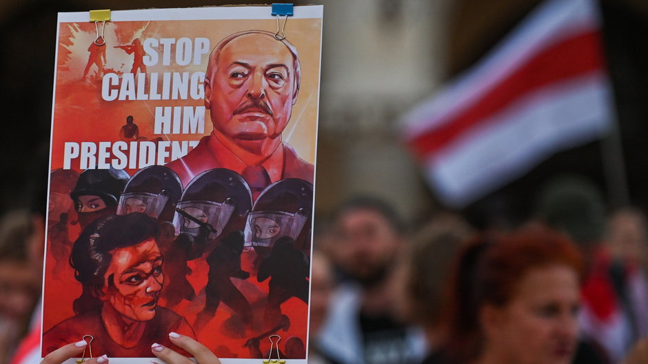 Protestujący trzymający plakat z wizerunkiem białoruskiego przywódcy z napisem: "Przestańcie nazywać go prezydentem"