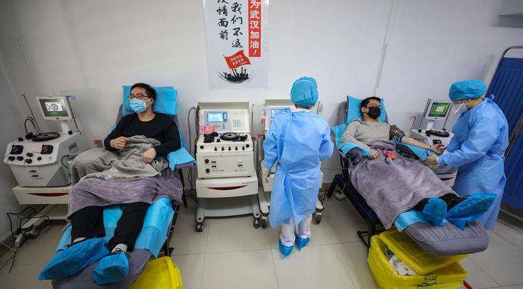 A koronavírus-fertőzésből kigyógyult Dr. Min Csou (b) és Dr. Kung Jüe-feng vért ad az egyik vuhani klinikán 2020. február 18-én