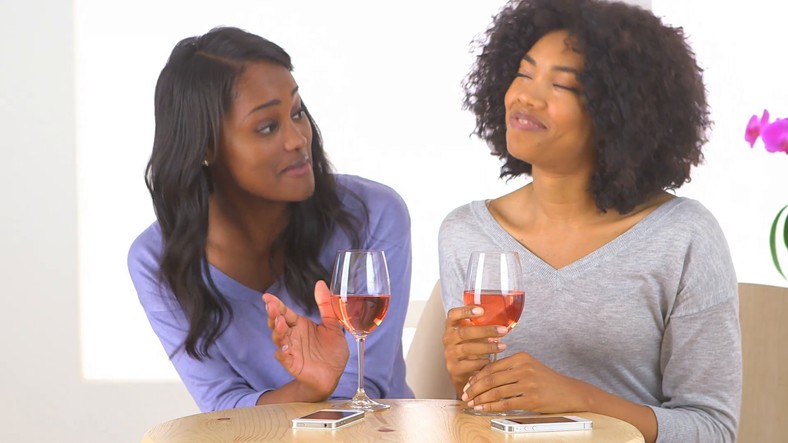 Friends having a chat over a bottle of wine [Credit: Video Blocks]