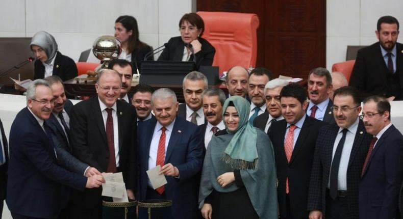 Turkey's Prime Minister Binali Yildirim (C) accompanied by lawmakers vote following a parliament debate on January 21, 2017 on proposed amendments to the country's constitution