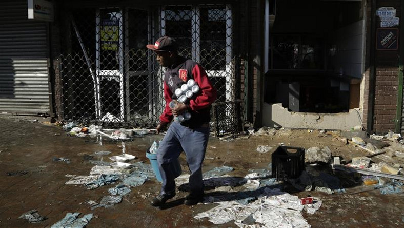 A looter makes off with goods from a store in Germiston, east of Johannesburg, South Africa [Themba Hadebe/The Associated Press]