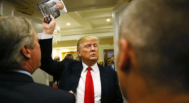 Republican presidential candidate Donald Trump holds up his book after holding a press conference at the Trump National Golf Club Jupiter on March 8, 2016 in Jupiter, Florida.