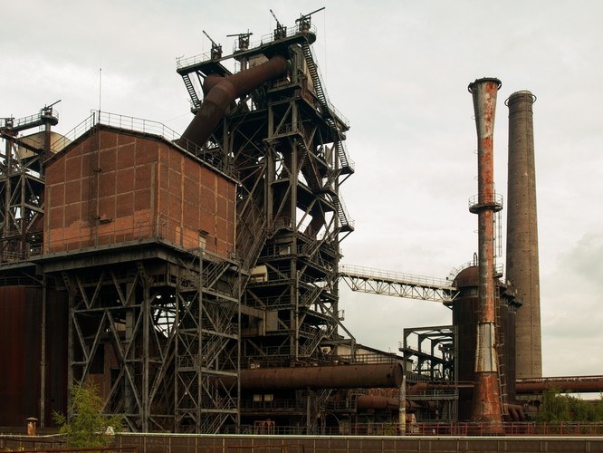 Prognozy naszych przodków dotyczące rozwoju przemysłu były z pewnością idealistyczne. 'Znikną dymne kominy i buchające żarem wielkie piece (...), metale topić się będą w wielkich piecach elektrycznych, (...) robotnicy w warsztatach swoich będą stać przy pracy w białych płaszczach (...), a na terenach przemysłowych, obecnie przedstawiających tak ponury obraz, rozciągać się będą zielone, wesołe parki i pola'. <br>Podobnie przyszłość widział brytyjski konserwatysta Frederick Edwin Smith: 'fabryki zostaną zdecentralizowane, a (...) cały kraj przeobrazi się w jeden olbrzymi park narodowy'. <br> Lord Birkenhead, jak dalej pisze IKC, sądzi, że chociaż brytyjski przemysł ulegnie radykalnej zmianie, to 'Anglja - dzięki swemu pomyślnemu położeniu geograficznemu i oparciu o dominja – zachowa nadal swą światową pozycję'. Na zdj. Stare zabudowania fabryczne