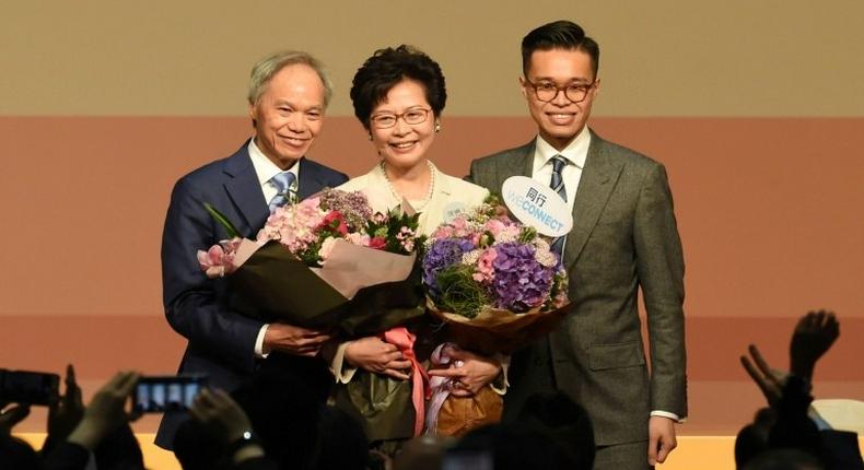 Hong Kong's new chief executive Carrie Lam (C) has pledged to mend political rifts after winning a vote dismissed as a sham by democracy activists