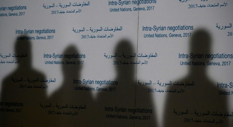 Shadows of members of Syria's main opposition High Negotiations Committee are casted on a backdrop during a press conference on Syria peace talks on February 27, 2017, in Geneva