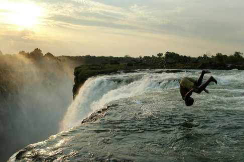 A Zambian man somersaults into a pool at the edge of the 110 metre high main falls of the Victoria F