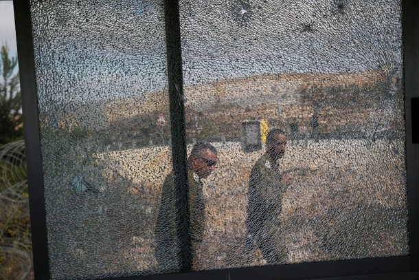 Israeli soldiers are seen through the window of a security booth damaged during a shooting attack in