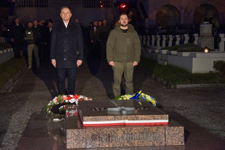 Prezydent RP Andrzej Duda (L) oraz prezydent Ukrainy Wołodymyr Zełenski (P) składają kwiaty na Mogile Pięciu Nieznanych z Persenkówki podczas wizyty na Cmentarzu Orląt Lwowskich (11.01.2023)