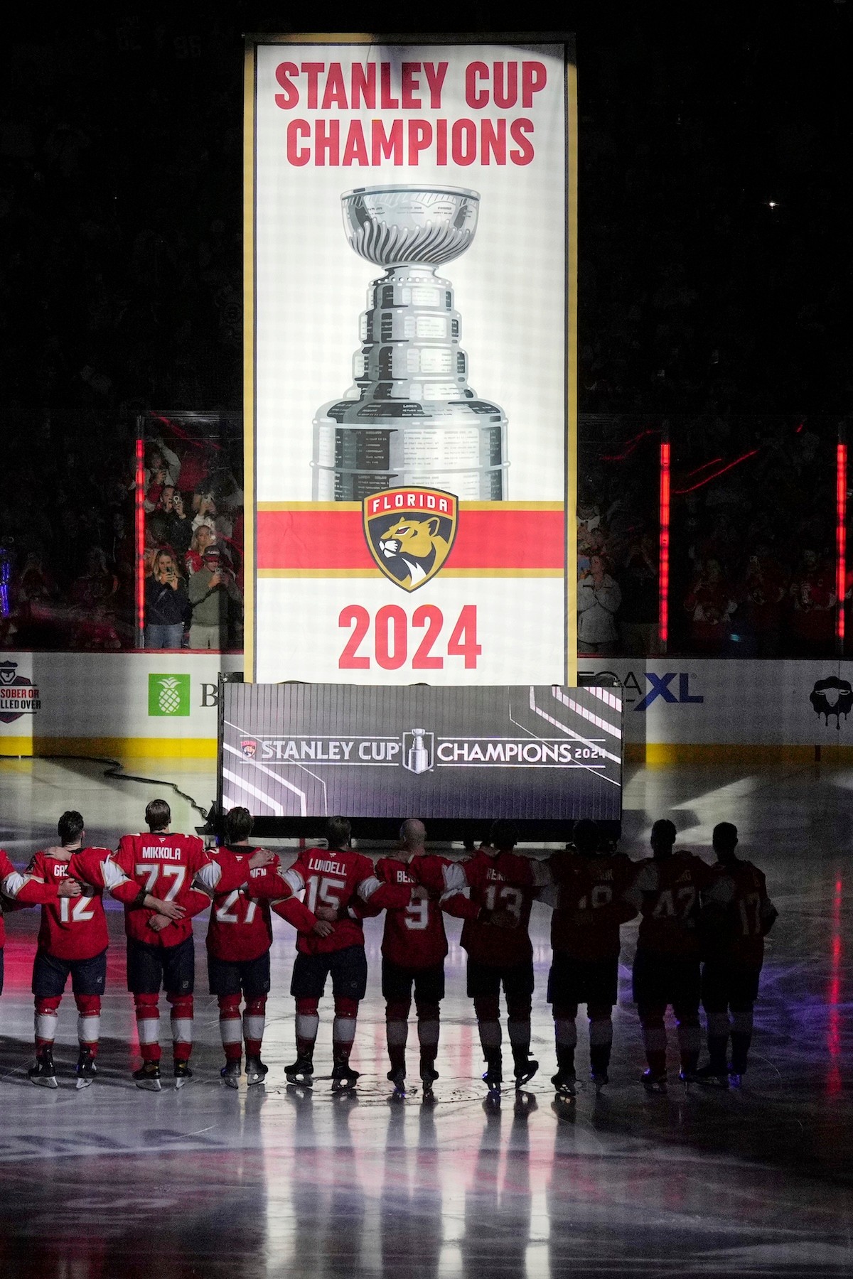 Obhajcovia Stanleyho pohára hokejisti Floridy Panthers stoja pri vztýčenej klubovej vlajke počas slávnostnej ceremónie pred začiatkom zápasu proti Bostonu Bruins.