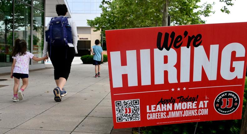 People walk past a now hiring sign posted outside of a restaurant in Arlington, Virginia on June 3, 2022.Olivier Douliery/AFP/Getty Images