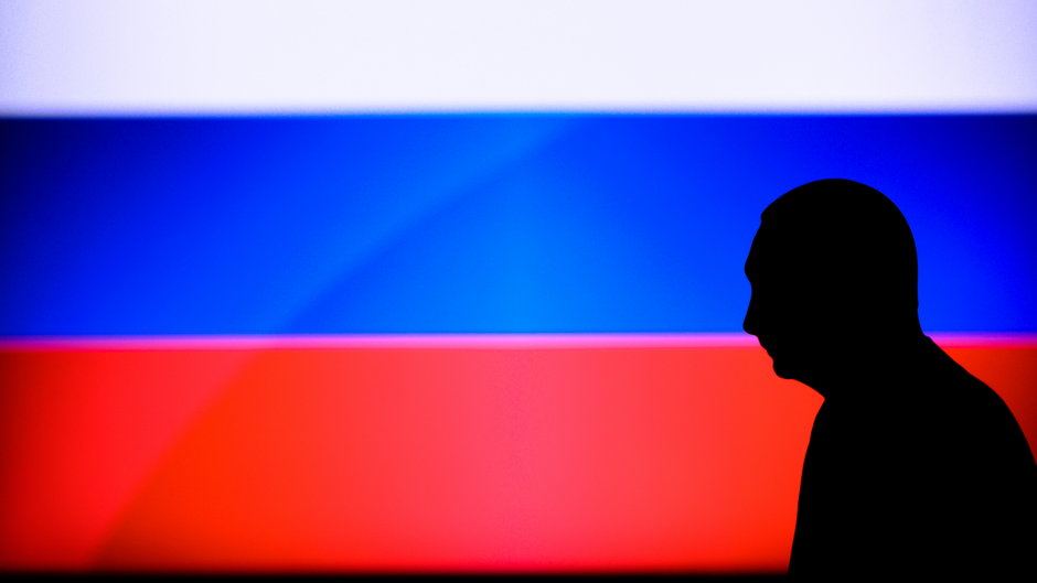 Cień Władimira Putina na tle rosyjskiej flagi