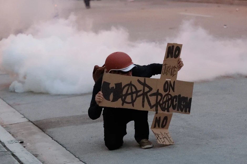 Demonstrant u Majamiju krije se iza transparenta kako bi izbegao gumene metke