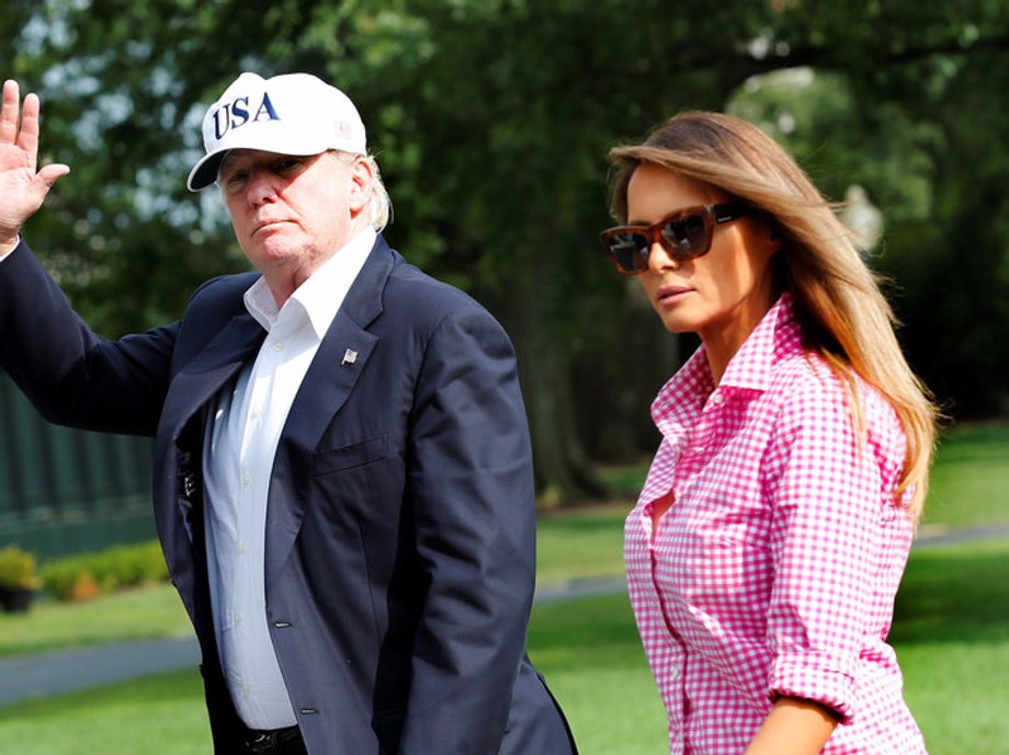 President Donald Trump waves as he walks with first lady Melania Trump on South Lawn of the White House in Washington