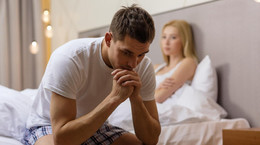 upset man sitting on bed with disappointed woman