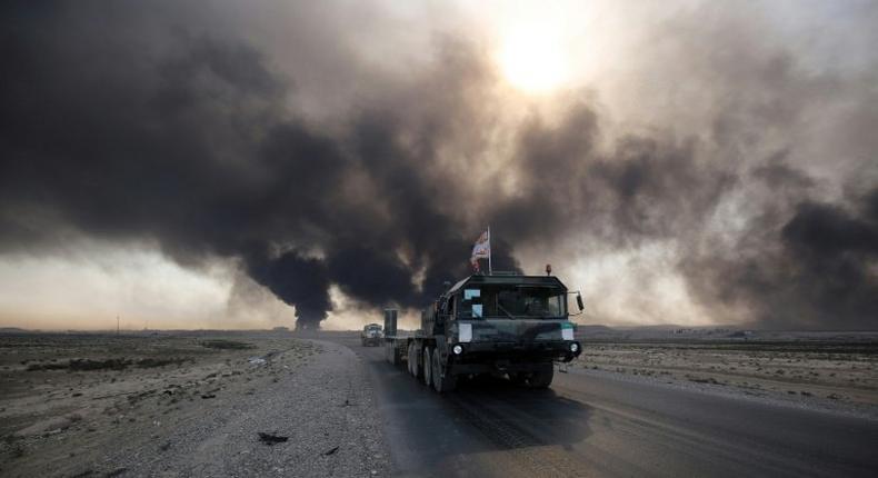 Iraqi army vehicle drives down a road east of Mosul, northern Iraq, on October 22, 2016, as displaced families flee areas of unrest during an operation to retake the city from Islamic State (IS) group jihadists