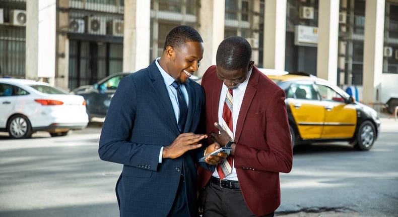 Two friends looking at the screen of a cellphone [Image Credit: Libasse El Arbi Ndoye]