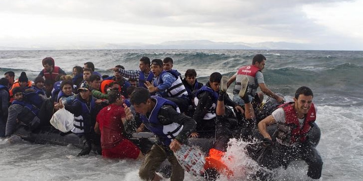 Refugees and migrants struggle to jump off an overcrowded dinghy on the Greek island of Lesbos, after crossing in rough seas from the Turkish coast