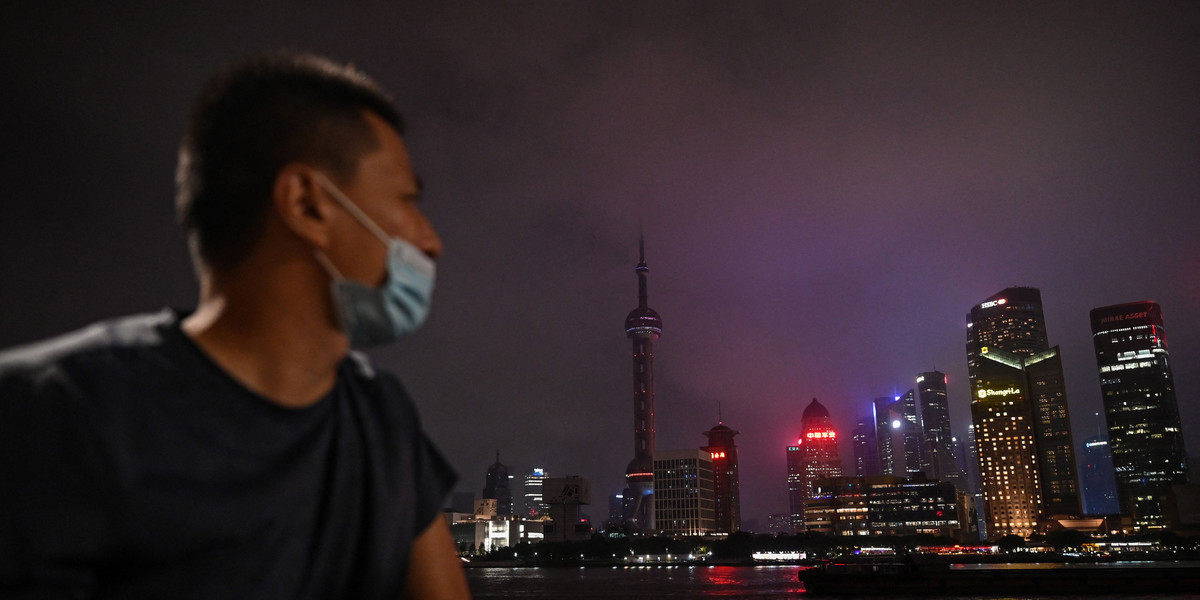 Mężczyzna spogląda z promenady Bund wzdłuż rzeki Huangpu, gdzie dekoracyjne światła są wyłączane w ramach oszczędzania energii w Szanghaju 23 sierpnia 2022 r.