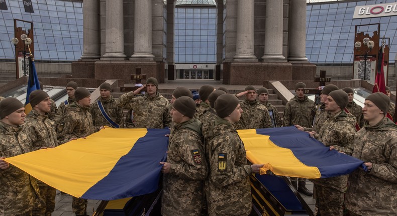 Soldiers hold Ukrainian flags over the coffins with Ukrainian servicemen Oleh Khomiuk and his son, Mykyta Khomiuk, who were killed in Bakhmut, during their funeral service at Independence Square on March 10, 2023 in Kyiv, Ukraine.Roman Pilipey/Getty Images