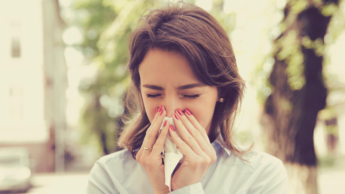 Woman with allergy symptoms blowing nose