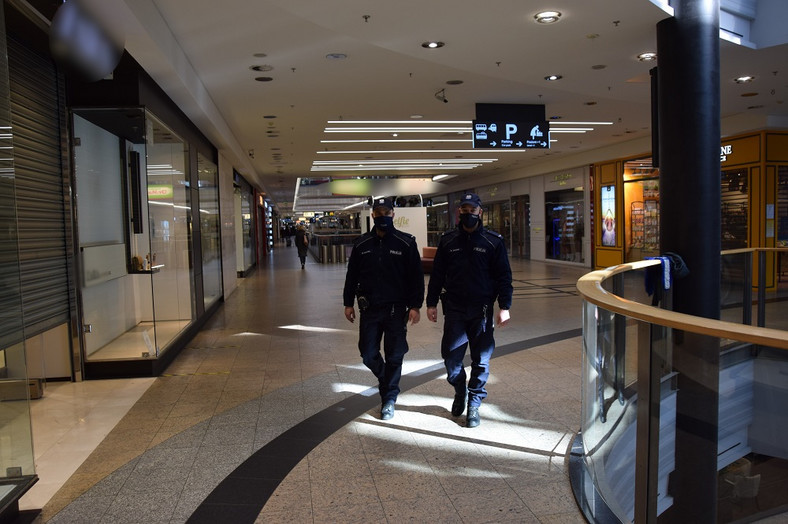 Policjanci kontrolujący przestrzeganie obowiązujących przepisów sanitarnych w otwartych lokalach galerii handlowej