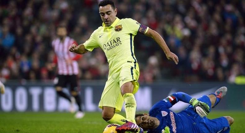 Barcelona's Xavi Hernandez passes Athletic Bilbao goalkeeper Gorka Iraioz during their Spanish first division soccer match at San Mames stadium in Bilbao, February 8, 2015. REUTERS/Vincent West