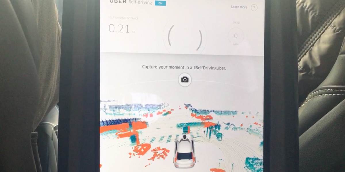 A screen in the back of the Uber shows what the self-driving cameras see in the world around the car. Here, cars pass in front of the Uber at an intersection in San Francisco.