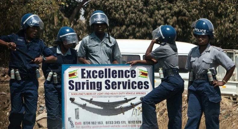 Zimbabwean police in anti-riot gear stand by a road sign as they patrol the streets as opposition protest for political reforms fails to kick off