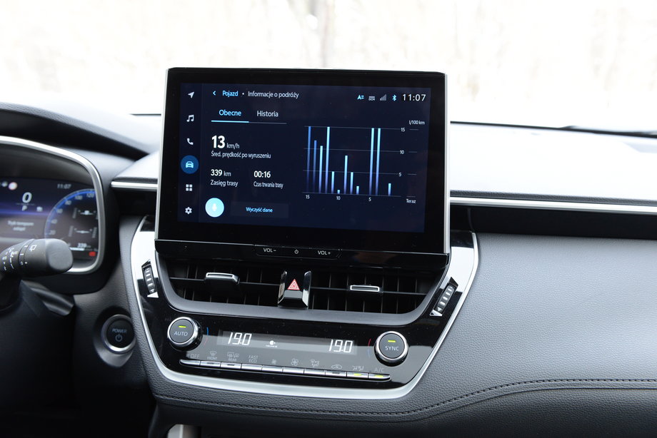 Toyota Corolla Cross - zgodnie z obecnym trendem, ekran systemu multimedialnego jest na szczycie środkowej konsoli. Pod nim znalazły się tradycyjne przyciski sterowania klimatyzacją.